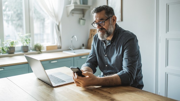 Online Bill Pay image of man paying bills on his phone from rome health near rome ny